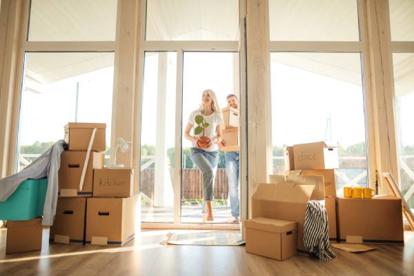 Happy young Couple Carrying Cardboard Boxes Into New Home On Moving Day